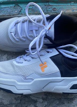 Кросівки fila trainer white з білим сітчастим верхом та помаранчевим логотипом.