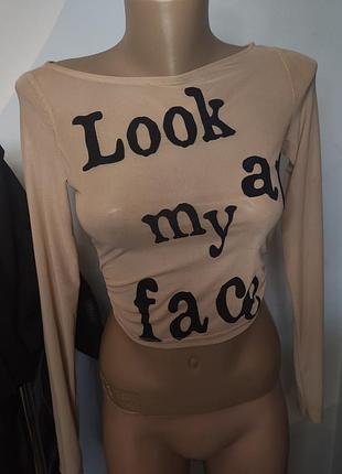 Бежевий топ від bershka має напис «look at my face» чорними літерами.