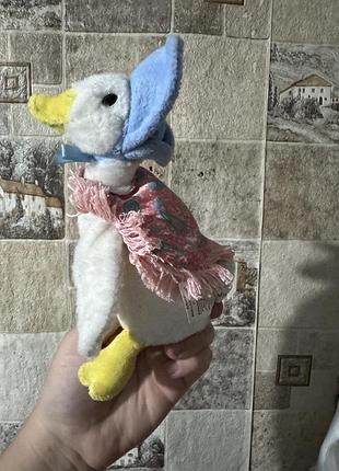 М'яка іграшка зображує качечку джемайму (jemima puddle-duck) з казок британської письменниці беатріс поттер, впізнавану за її блакитним чепчиком
