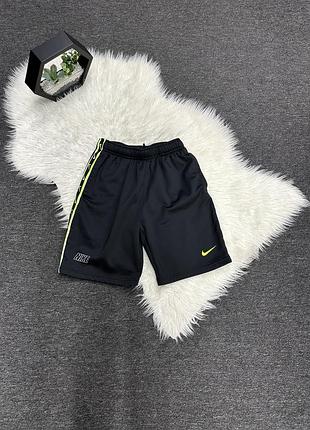 Чорні спортивні шорти nike з яскравими жовто-салатовими акцентами та фірмовими лампасами збоку.
