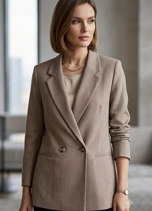 Жіночий двобортний жакет h&m у бежеву клітинку має класичний виріз з лацканами та прорізні кишені.