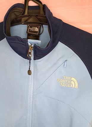 Женская флисовая куртка the north face tka stretch в бело-голубом и темно-синем цветах с воротником-стойкой и нагрудным карманом на молнии.