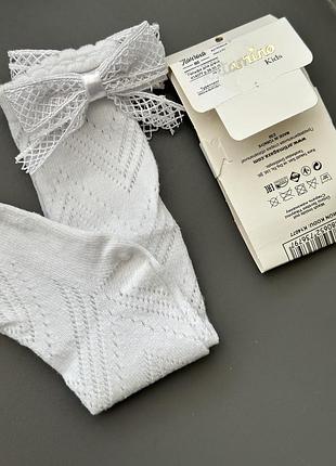 Білі дитячі гольфи katamino з ажурним візерунком та декоративним бантом.
