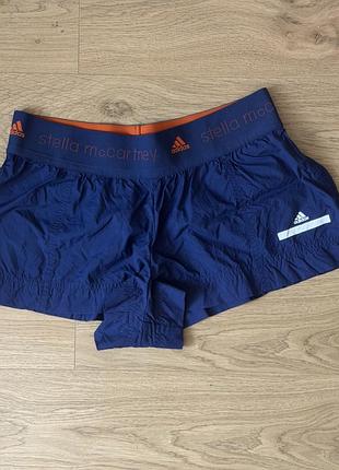 Спортивні шорти adidas by stella mccartney виконані у синьому кольорі з помаранчевим еластичним поясом.