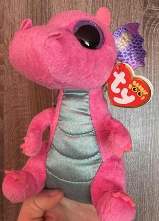 Це плюшева іграшка ty beanie boos у формі рожевого дракона на ім'я spitfire, що має фіолет...