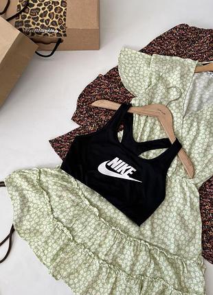 Чорний спортивний топ-бра nike з білим логотипом swoosh на грудях та спинкою-борцовкою.