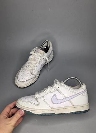 Кросівки nike dunk low, що мають білий шкіряний верх із фіолетовим логотипом