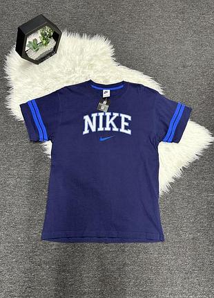 Темно-синя чоловіча футболка nike у вінтажному університетському стилі (varsity/collegiate) з великим світлим написом «nike» та міні-логотипом swoosh