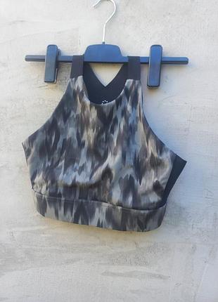 Спортивный топ varley sherman sports bra с высоким горлом и камуфляжным принтом в серо-зеленых оттенках.