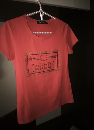 Брендовая женская футболка gucci в ярком кораллово-розовом оттенке с фирменным золотистым принтом-логотипом, красиво мерцающим.