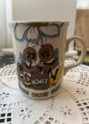 Чашка з милим вінтажним малюнком бджілок, що їдять мед, та написом «quince honey farm».quince honey farm —відома пасіка у північному девоні (англія).