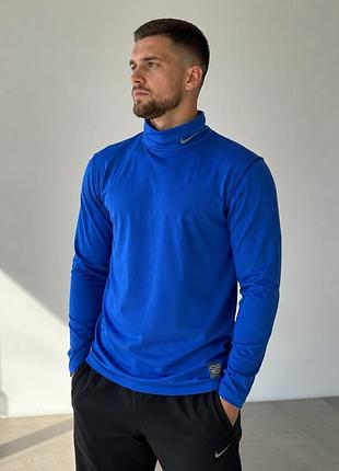 Це яскраво-синій спортивний лонгслів nike pro combat dri-fit із коміром-стійкою та фірмовим логотипом на горловині.