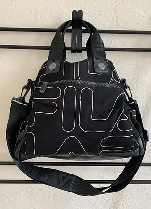 Чорна жіноча сумка бренду fila, прикрашена великим фірмовим логотипом у вигляді білих ліній контуру.