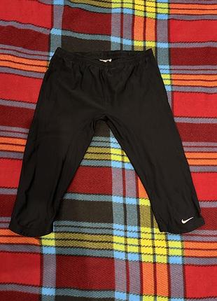 Чорні спортивні капрі/легінси 3/4 від бренду nike з білим логотипом swoosh на нижній частині штанини.