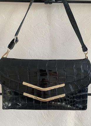 Чорна сумка - клатч від бренду lancel paris, виготовлену зі штучної шкіри з тисненням під крокодила.
