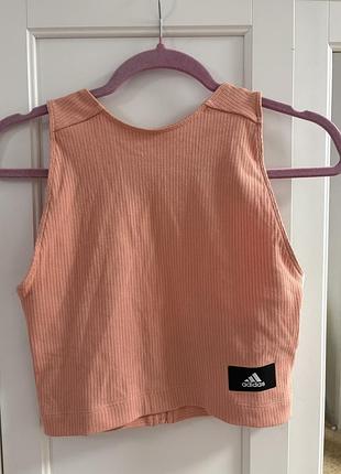Персиковий ребристий крос-топ adidas sportswear crop rib tank top із чорним фірмовим логотипом на нижній частині.