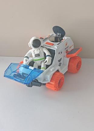 Игровой набор исследователя космоса, состоящий из белого марсохода (лунохода) с синим стеклом кабины и оранжевыми колёсами, и фигурки космонавта