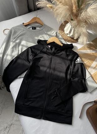 Чорна спортивна кофта (зип-худі) бренду adidas на блискавці, з капюшоном та білим фірмовим логотипом badge of sport на лівому плечі.