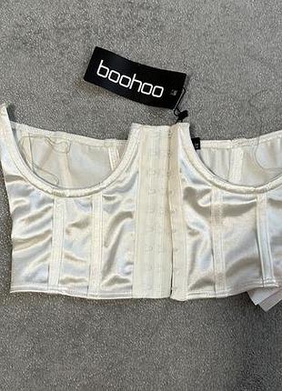 Білий атласний корсетний топ-бюстьє бренду boohoo з кісточками та застібкою на гачках спереду.