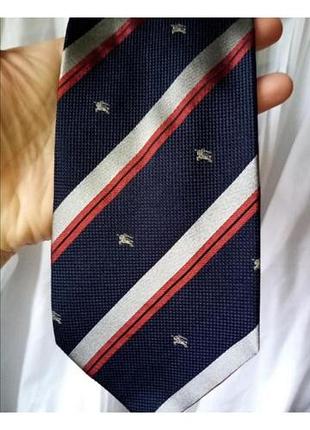 Шелковый винтажный галстук burberry с диагональными синими, серебристыми и красными полосами и мелким принтом в виде фирменного эгвестраннайта