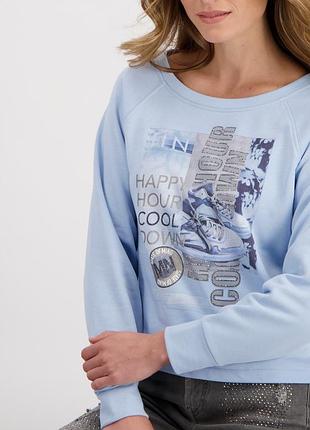 Світло-блакитний світшот від бренду monari з принтом кросівок і написами «happy hour cool down