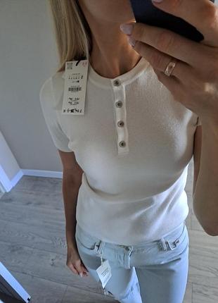 Біла вязана футболка поло zara з ґудзиками.