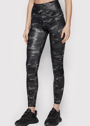 На зображенні показано жіночі легінси nike w nk one df camo mr tgt з блискучим чорно-сірим камуфляжним принтом.