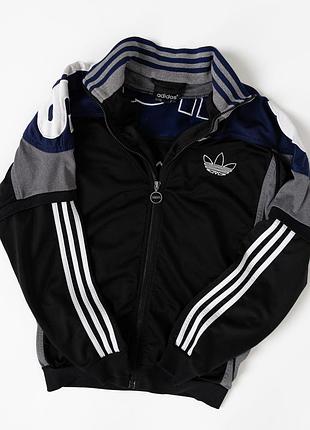 Вінтажна, чоловіча, спортивна олімпійка adidas у класичному ретро-дизайні. основний колір чорний, доповнений сірими та темно-синіми вставками, фірмо