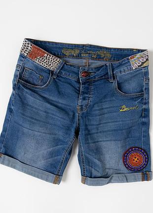 Жіночі, джинсові шорти desigual у синьому кольорі з оригінальним, декоративним оформленням. модель виконана з деніму з легким ефектом потертості та до