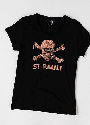 Стильна, жіноча футболка st. pauli у класичному, чорному кольорі з виразним, графічним принтом черепа та схрещених кісток у мідно-рожевому відтінку.