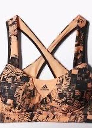 Спортивный  женский топ от adidas оранжево-черного цвета с графическим принтом и перекрещивающимися бретелями на спине.