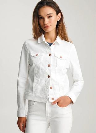 На фото зображена класична біла джинсова куртка (denim jacket), яка є базовим та універсальним елементом гардероба