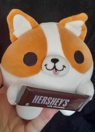М'яка іграшка zuru snackles (серія mini brands) у вигляді кумедного коргі на ім'я бенджі, який тримає в лапках шоколадний батончик.