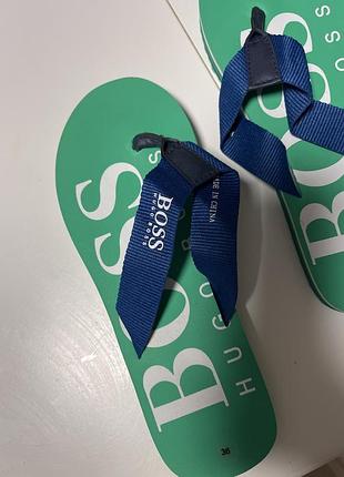 Зелені в'єтнамки boss (hugo boss) з синіми текстильними ремінцями та великим білим логотипом на підошві.
