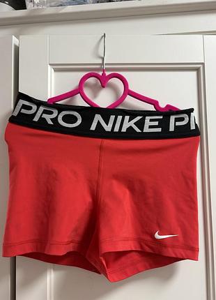 Червоні жіночі спортивні шорти nike pro з чорним еластичним поясом і білим логотипом.