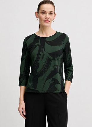 Жіночий топ marimekko у темно-зеленому та чорному кольорах із виразним, абстрактним візерунком. модель має круглу горловину, рукави довжиною 3/4 та п