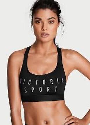 Чёрный спортивный топ victoria sport с блестящим серебристым логотипом на передней части.