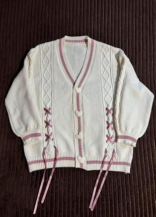 Білий в'язаний кардиган у стилі kawaii/coquette з рожевими акцентами, v-подібним вирізом, серцеподібними ґудзиками та довгими рожевими стрічками.