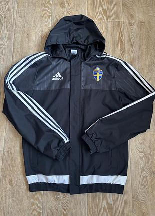 Чорну спортивну вітровку/дощовик adidas із капюшоном та емблемою шведського футбольного союзу (svff) на грудях.