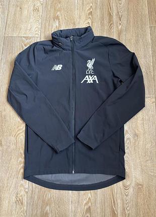 Сіра спортивна вітровка футбольного клубу liverpool fc сезону 2019/2020 від бренду new balance з логотипом спонсора axa