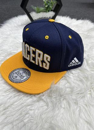 Темно-синю бейсболку adidas з жовтим козирком та написом «pacers» спереду.