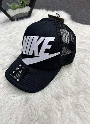 Чорна кепка-тракер nike rise із сітчастою задньою частиною та великим білим логотипом на передній панелі.