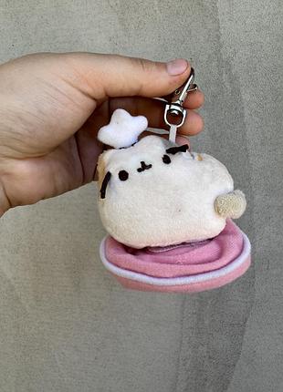 Плюшевий брелок-іграшку кіт пушин (pusheen) із серії «places cats sit» (серія 3) від виробника gund, де котик сидить на рожевій подушці