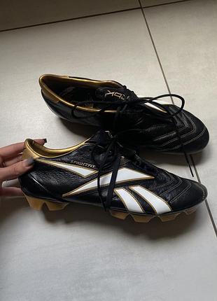 Футбольні бутси reebok sprintfit pro ii fg у чорному кольорі з білим логотипом та золотими акцентами