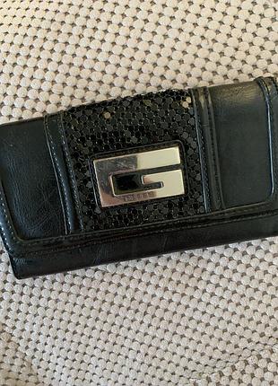 Чорний довгий жіночий гаманець бренду guess із металевою пряжкою-логотипом та текстурованою центральною вставкою.