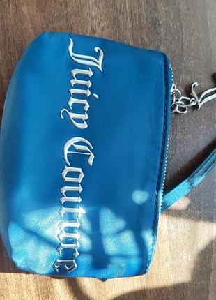 Синя нейлонова міні-сумочка чи косметичка від бренду juicy couture з білим фірмовим логотипом на передній частині та металевим брелоком на блискавці.