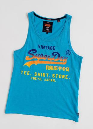 Чоловіча, блакитна майка superdry з великим, оригінальним принтом на передній частині. модель виконана у насиченому, блакитному кольорі та