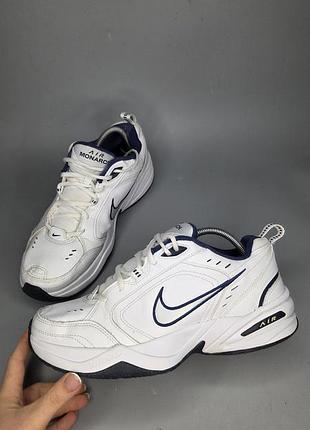 Белые мужские кроссовки nike air monarch iv с характерными темно-синими акцентами на логотипе и подошве