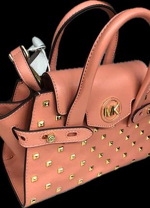 Рожева саф'янова сумка-сатчел моделі michael kors carmen у розмірі extra-small з клапаном, ремінцем та золотистими заклепками.