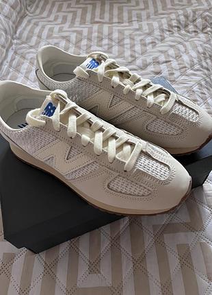 Це бежеві кросівки new balance 471 з фактурними сітчастими вставками та синім логотипом на язичку